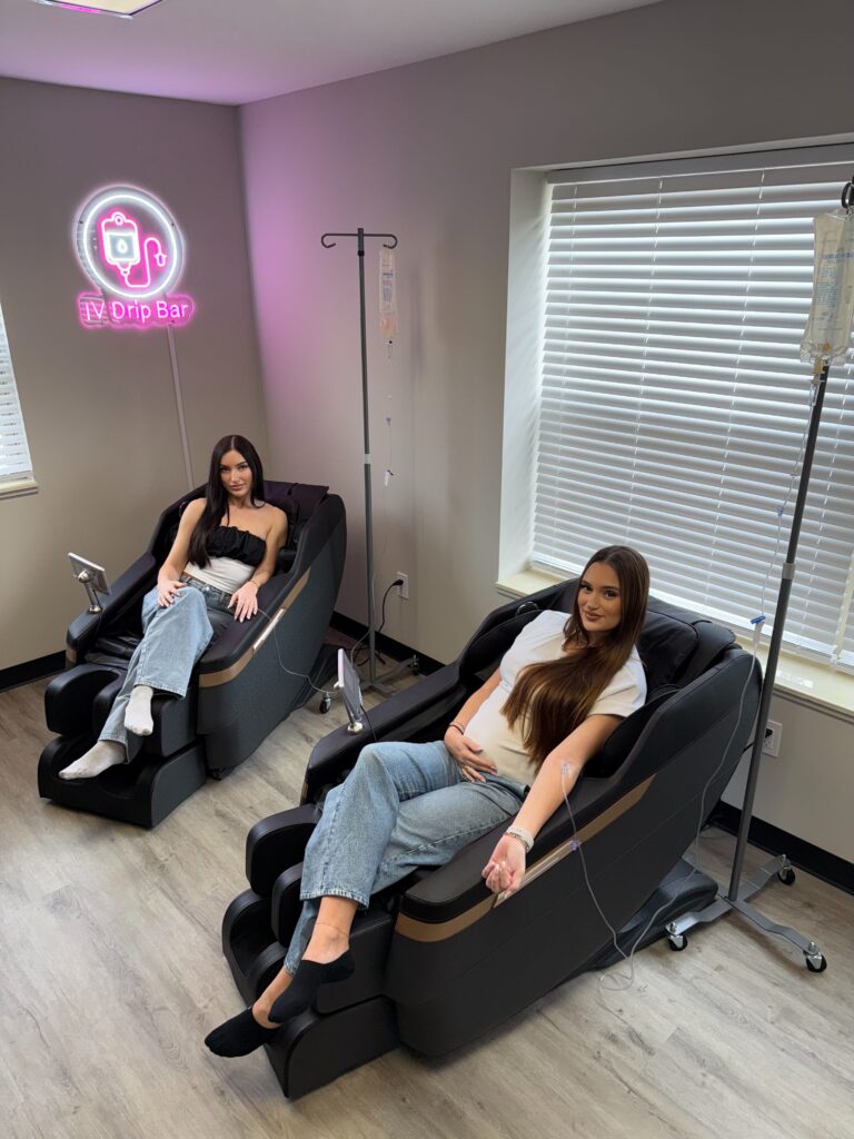 a woman sitting in a massage chair and getting IV therapy
