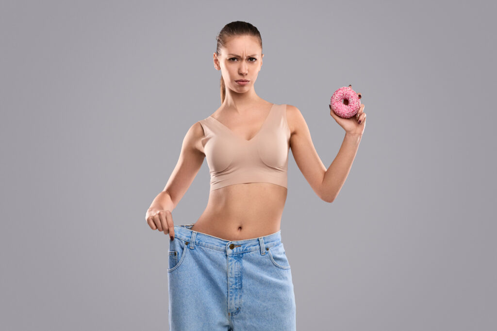 a woman holding a donut and waistline